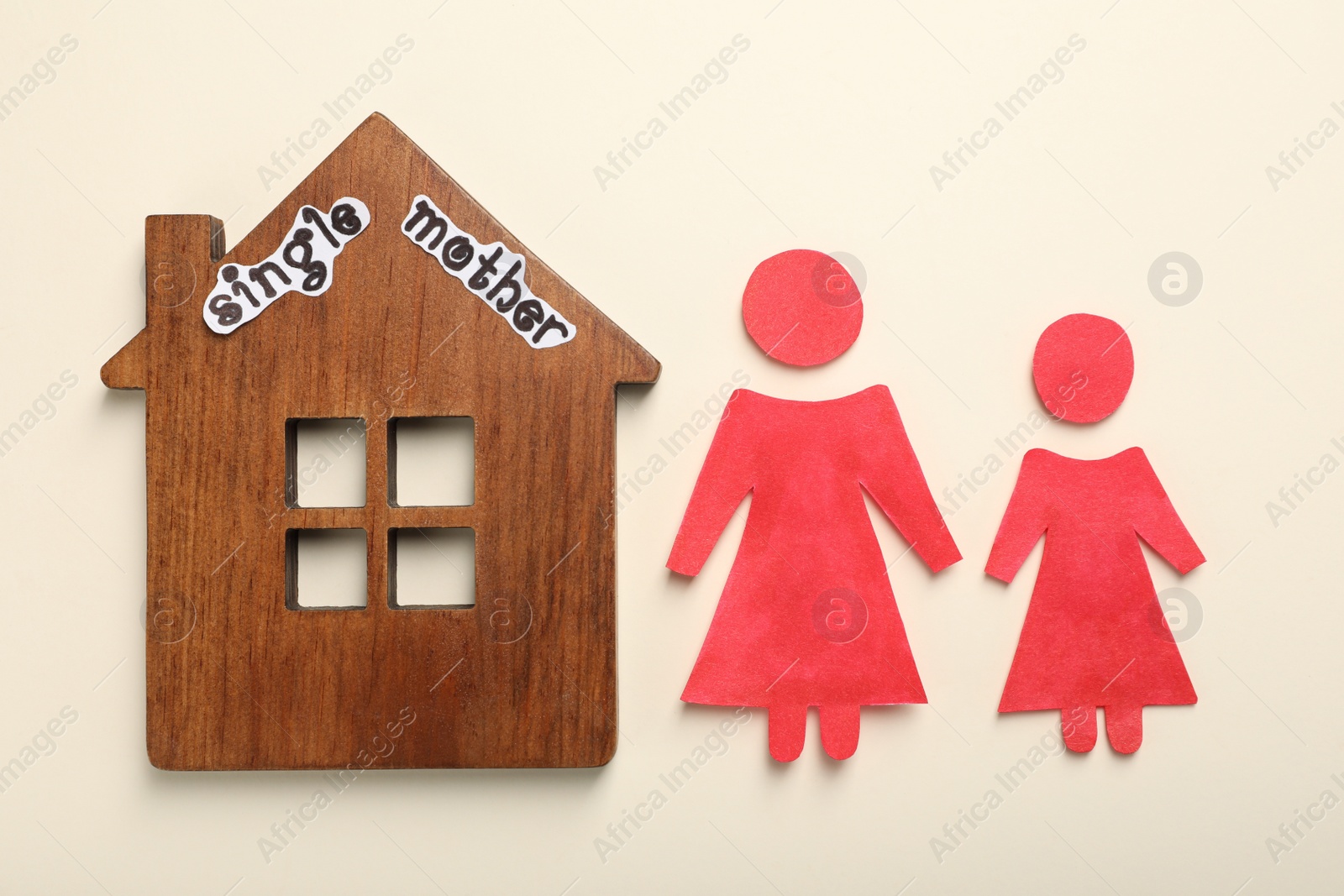 Photo of Being single mother concept. Woman with her child made of paper near wooden house on light background, flat lay