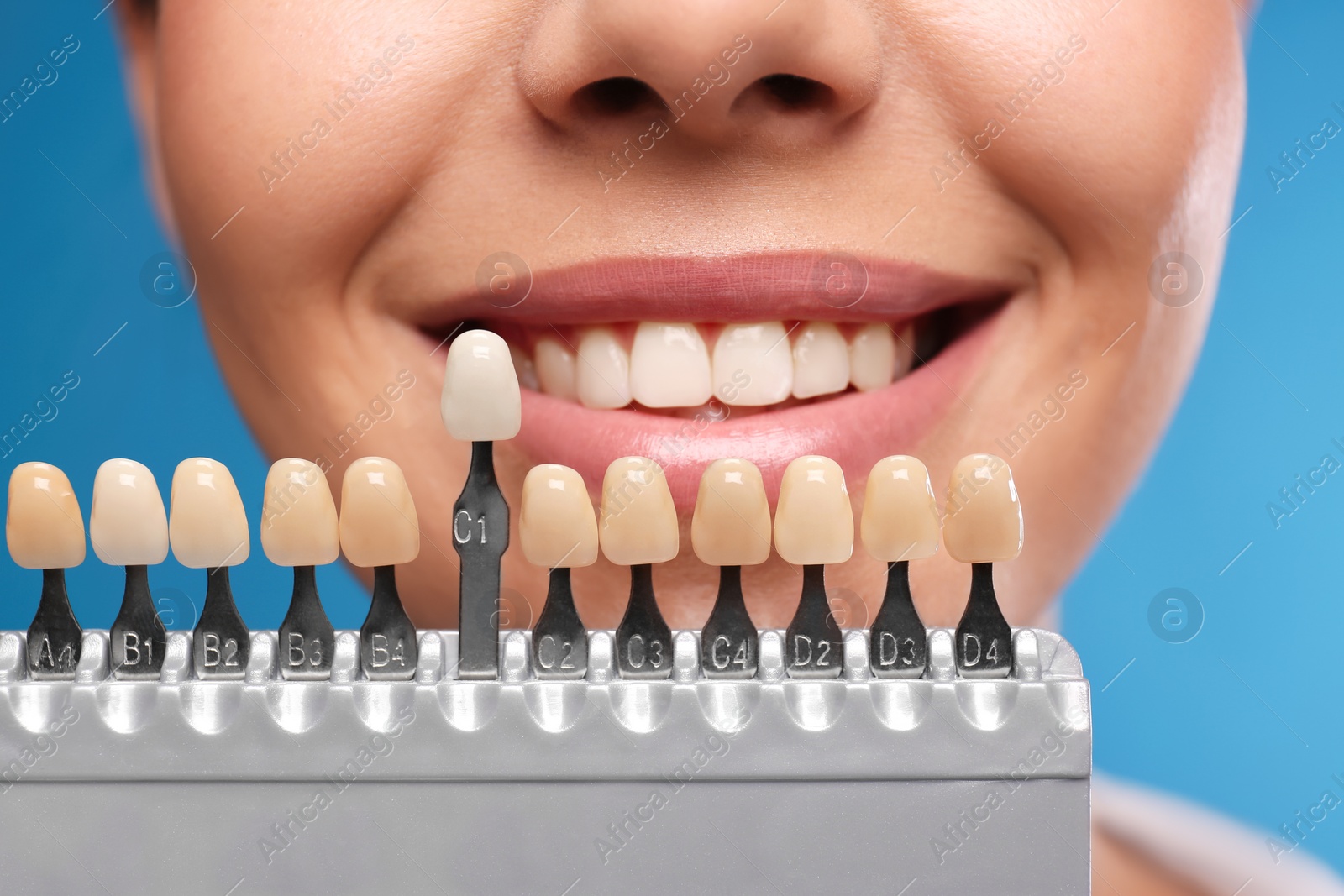 Photo of Woman checking her teeth color on blue background, closeup. Cosmetic dentistry