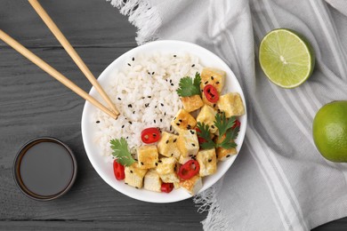 Delicious rice with fried tofu, chili pepper and parsley served on grey wooden table, flat lay