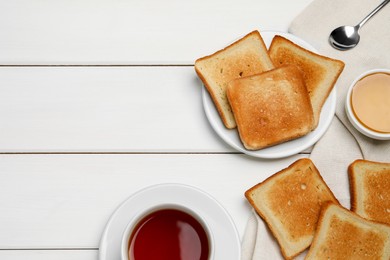 Photo of Slices of tasty toasted bread and aromatic tea on white wooden table, flat lay. Space for text