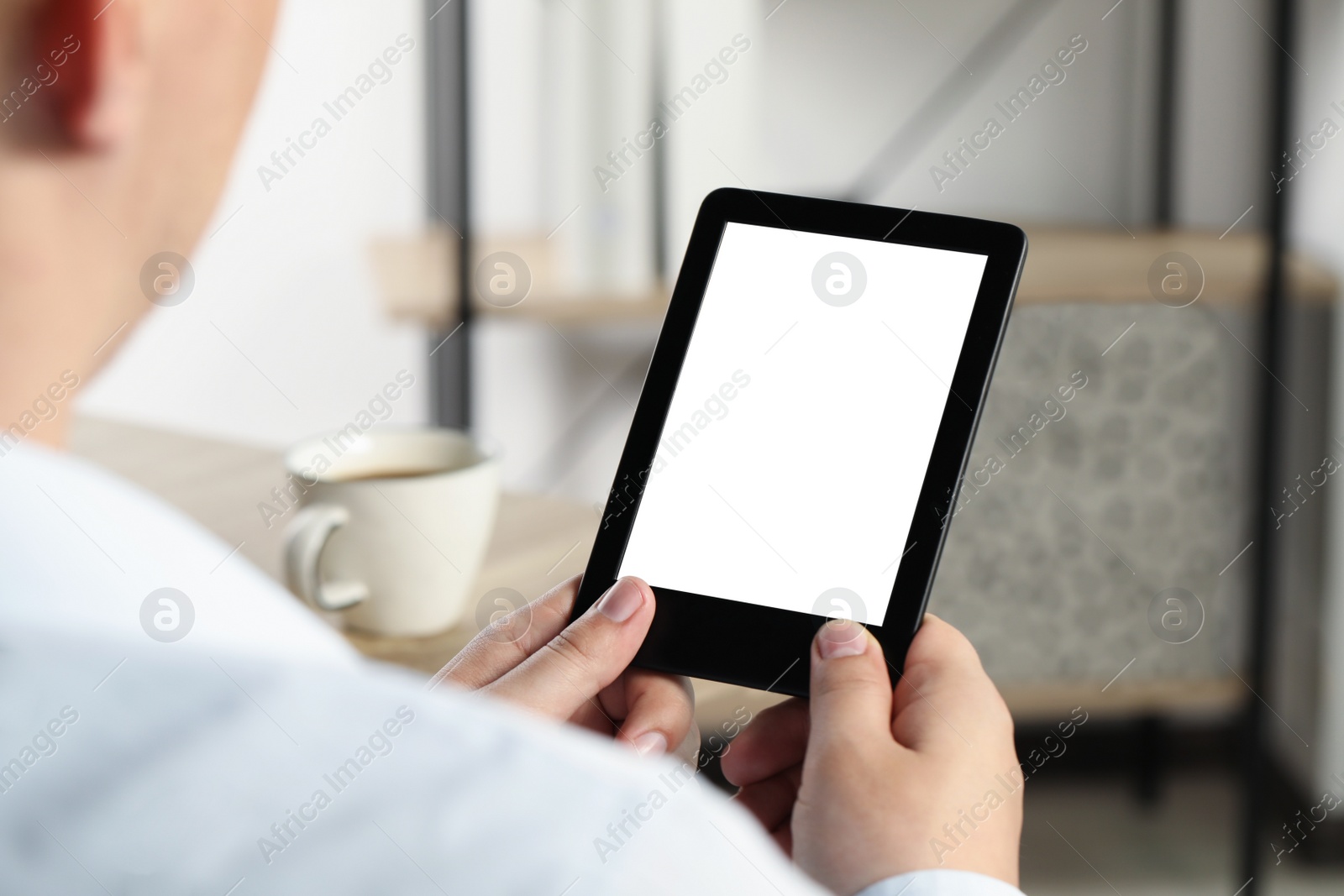 Photo of Man using e-book reader indoors, closeup view