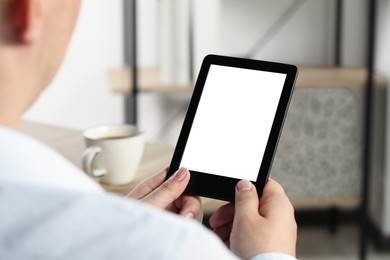 Man using e-book reader indoors, closeup view