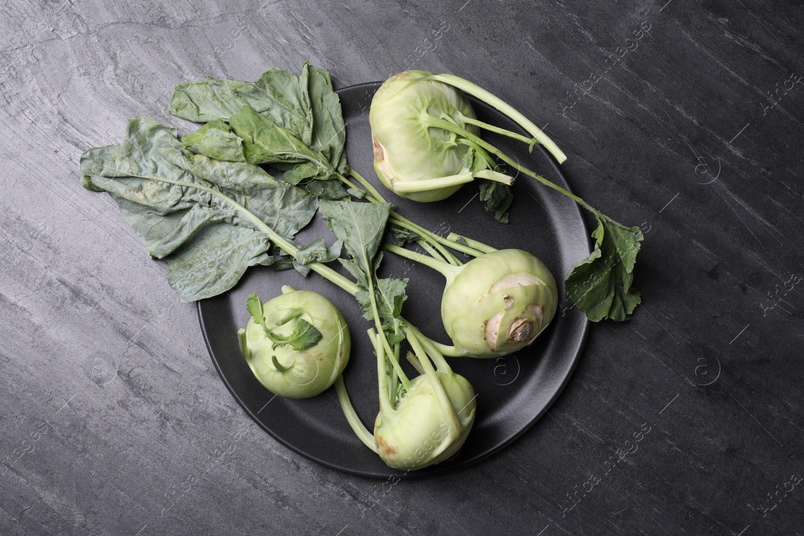 Photo of Whole ripe kohlrabi plants on grey table, top view