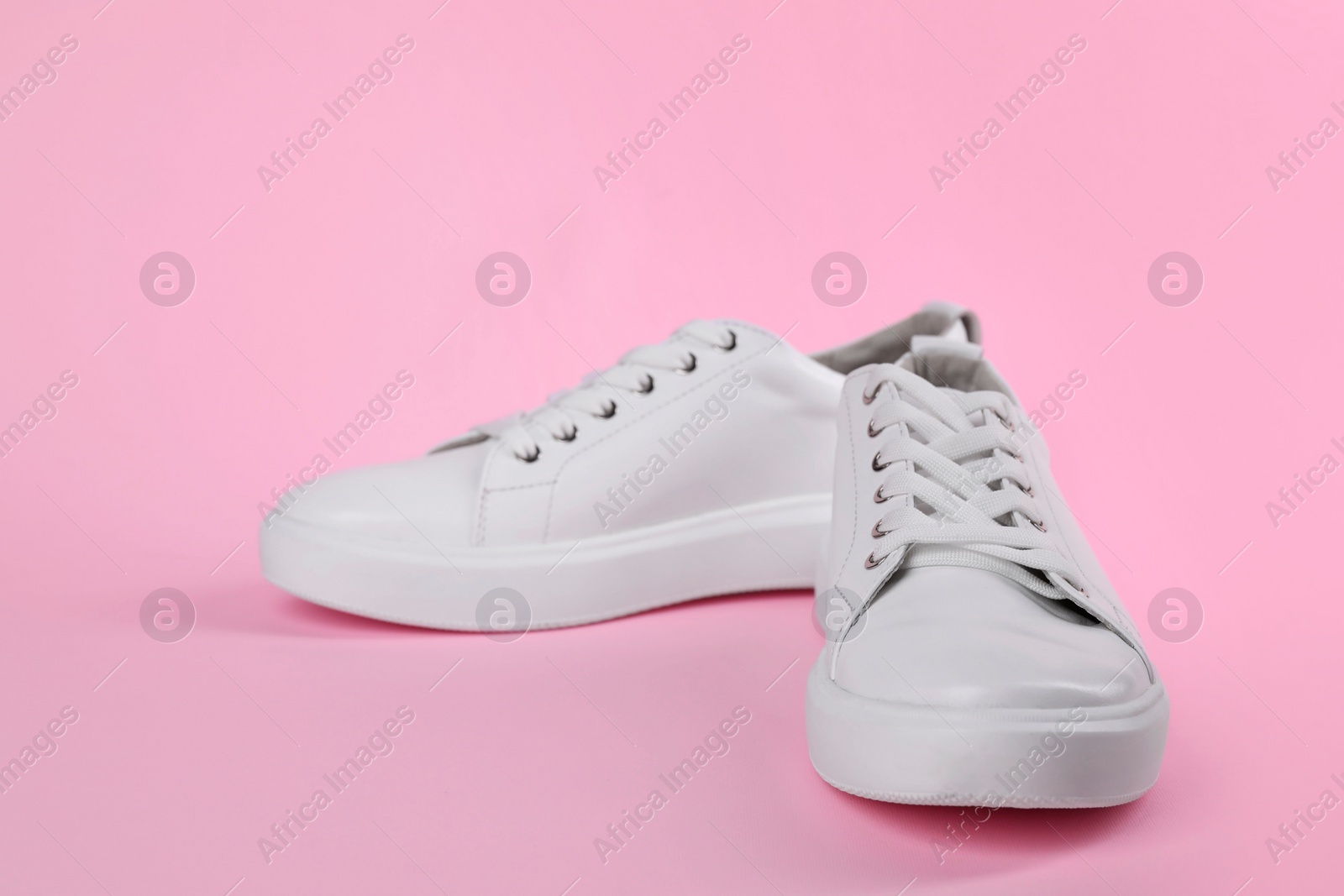 Photo of Pair of stylish white sneakers on pink background