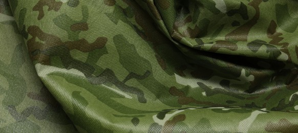 Photo of Texture of crumpled camouflage fabric as background, top view