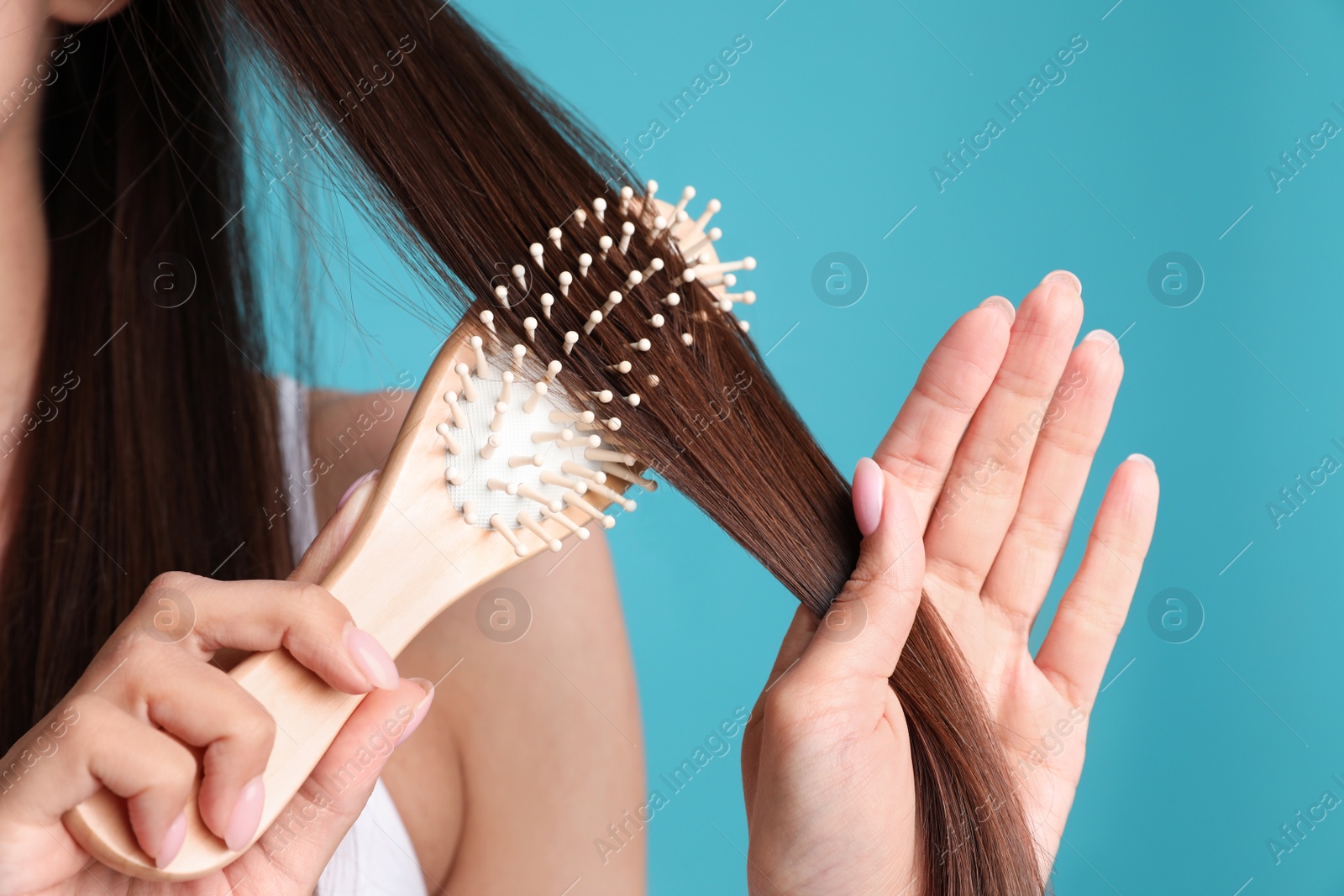 Photo of Woman with hair brush on color background, closeup