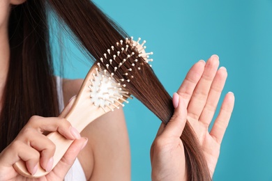 Photo of Woman with hair brush on color background, closeup