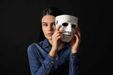 Multiple personality concept. Woman with mask on black background