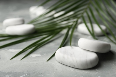 Photo of Spa stones and green leaf on grey background. Space for text