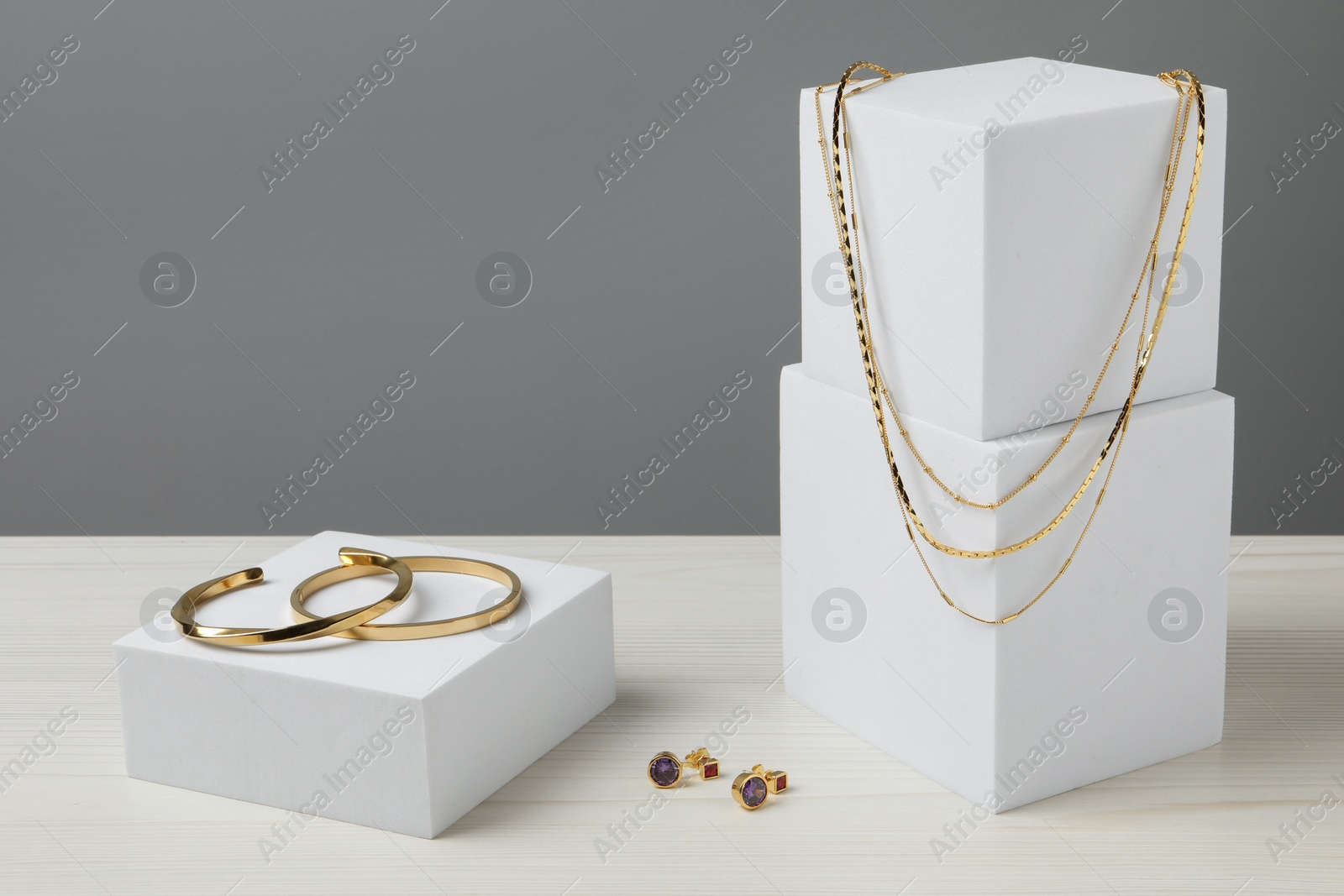 Photo of Stylish presentation of bracelets, necklace and earrings on white wooden table