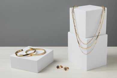 Stylish presentation of bracelets, necklace and earrings on white wooden table