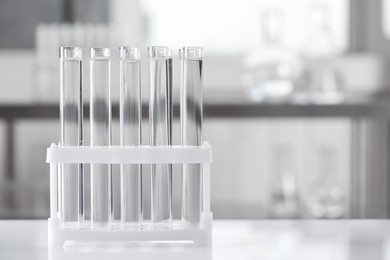 Photo of Test tubes with transparent liquid on table in laboratory. Space for text