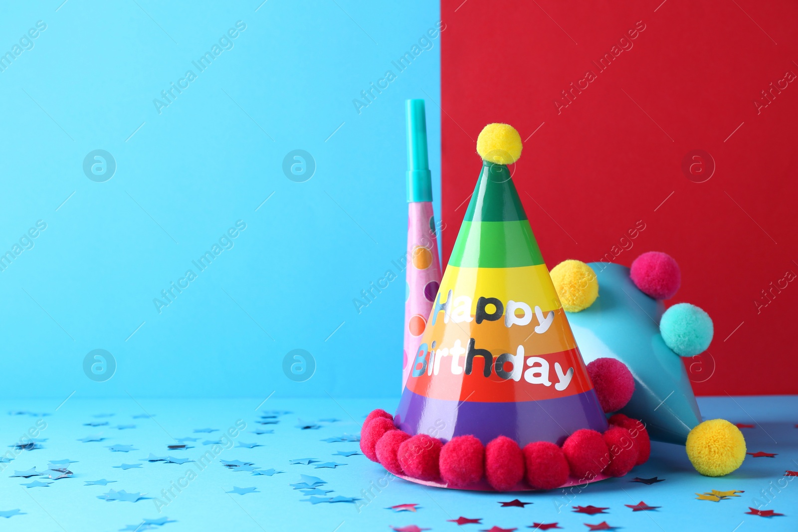 Photo of Party hats and confetti on color background, space for text