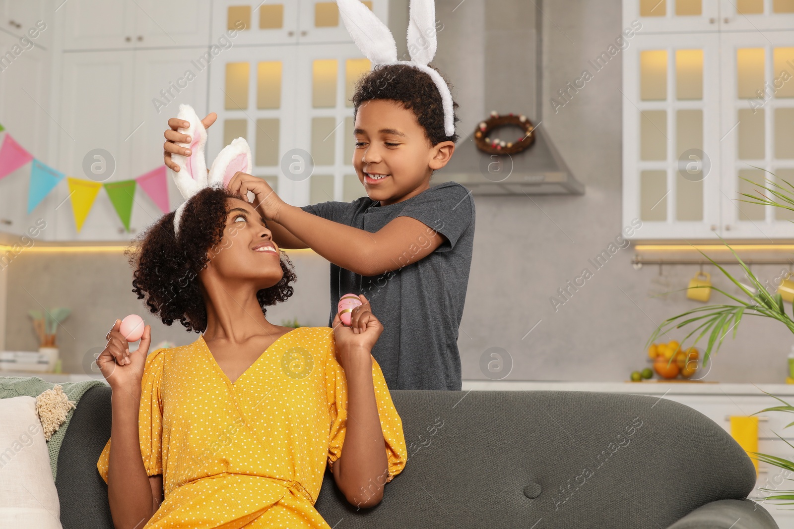 Photo of Happy African American mother with Easter eggs and her cute son in kitchen