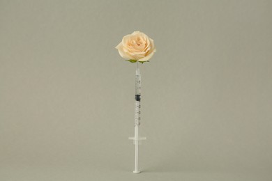 Photo of Medical syringe and rose flower on light grey background