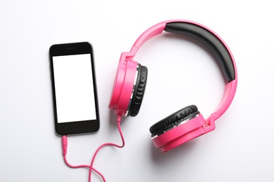 Stylish headphones and modern phone on white background, top view. Space for text