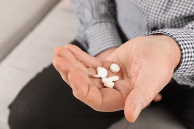 Photo of Senior man holding pills in hand, closeup