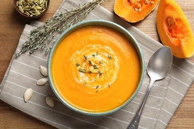 Photo of Flat lay composition with delicious pumpkin cream soup in bowl on wooden background