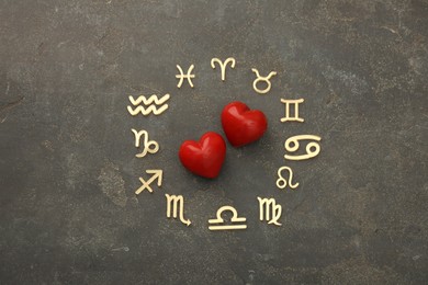 Photo of Zodiac signs and red hearts on grey textured background, flat lay