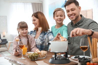 Photo of Happy family enjoying fondue dinner at home