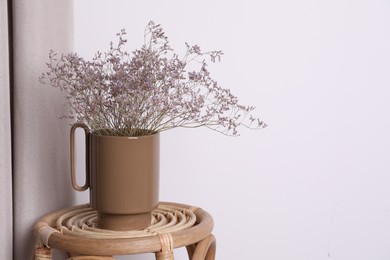 Photo of Ceramic vase with dry flowers on wicker table near white wall. Space for text