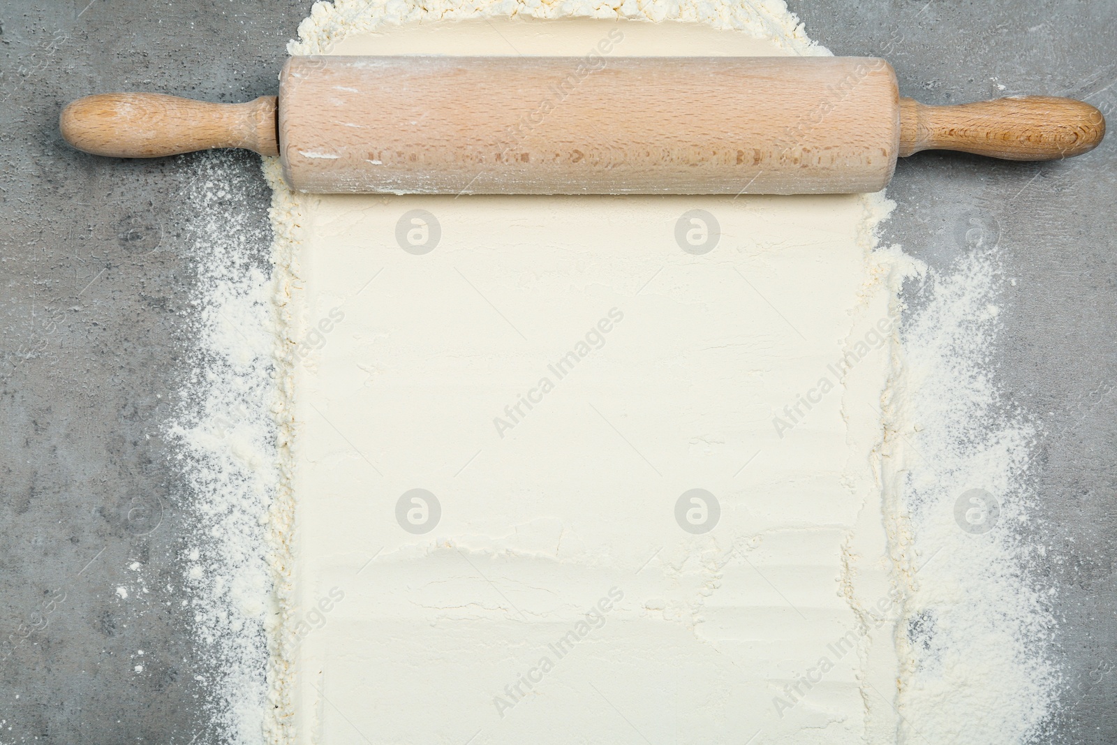 Photo of Flour and rolling pin on light grey table, top view. Space for text