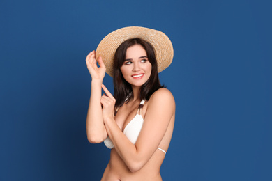 Photo of Beautiful woman in stylish bikini and hat on blue background