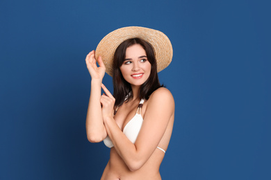 Beautiful woman in stylish bikini and hat on blue background