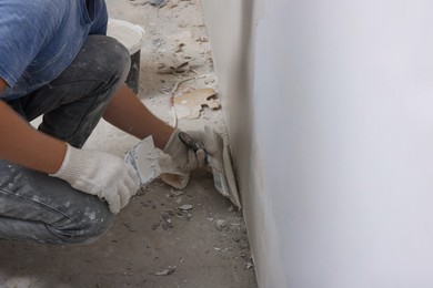 Photo of Worker plastering wall with putty knife indoors, closeup. Space for text