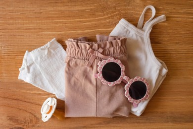 Photo of Stylish child clothes and accessories on wooden background, flat lay