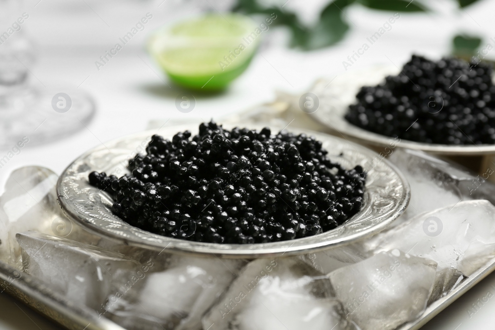 Photo of Plate with black caviar served with ice cubes on metal tray