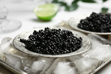 Photo of Plate with black caviar served with ice cubes on metal tray