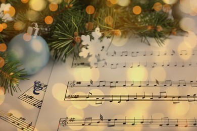Christmas and New Year music. Fir tree branch and festive decor on music sheets, bokeh effect