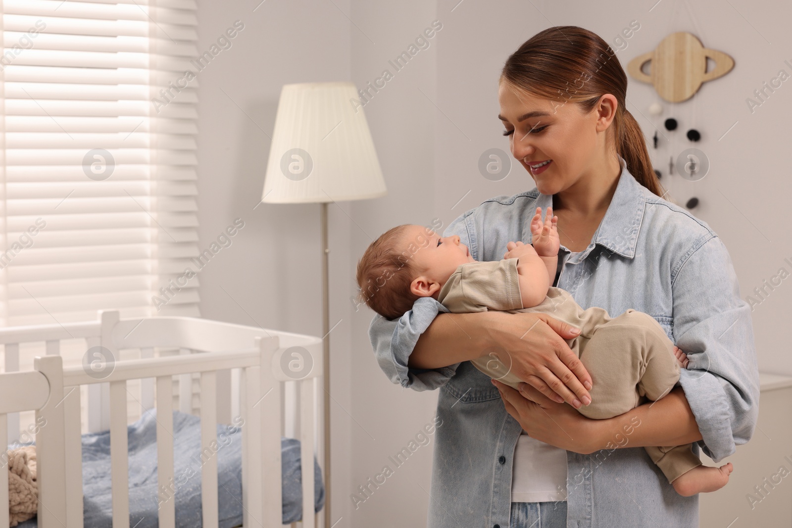 Photo of Mother holding her cute newborn baby in child's room