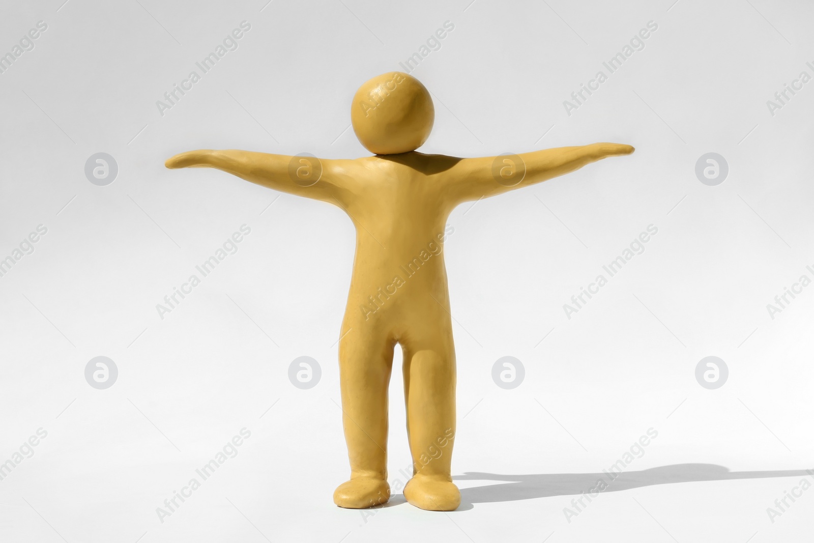 Photo of Human figure with arms wide open made of yellow plasticine on white background