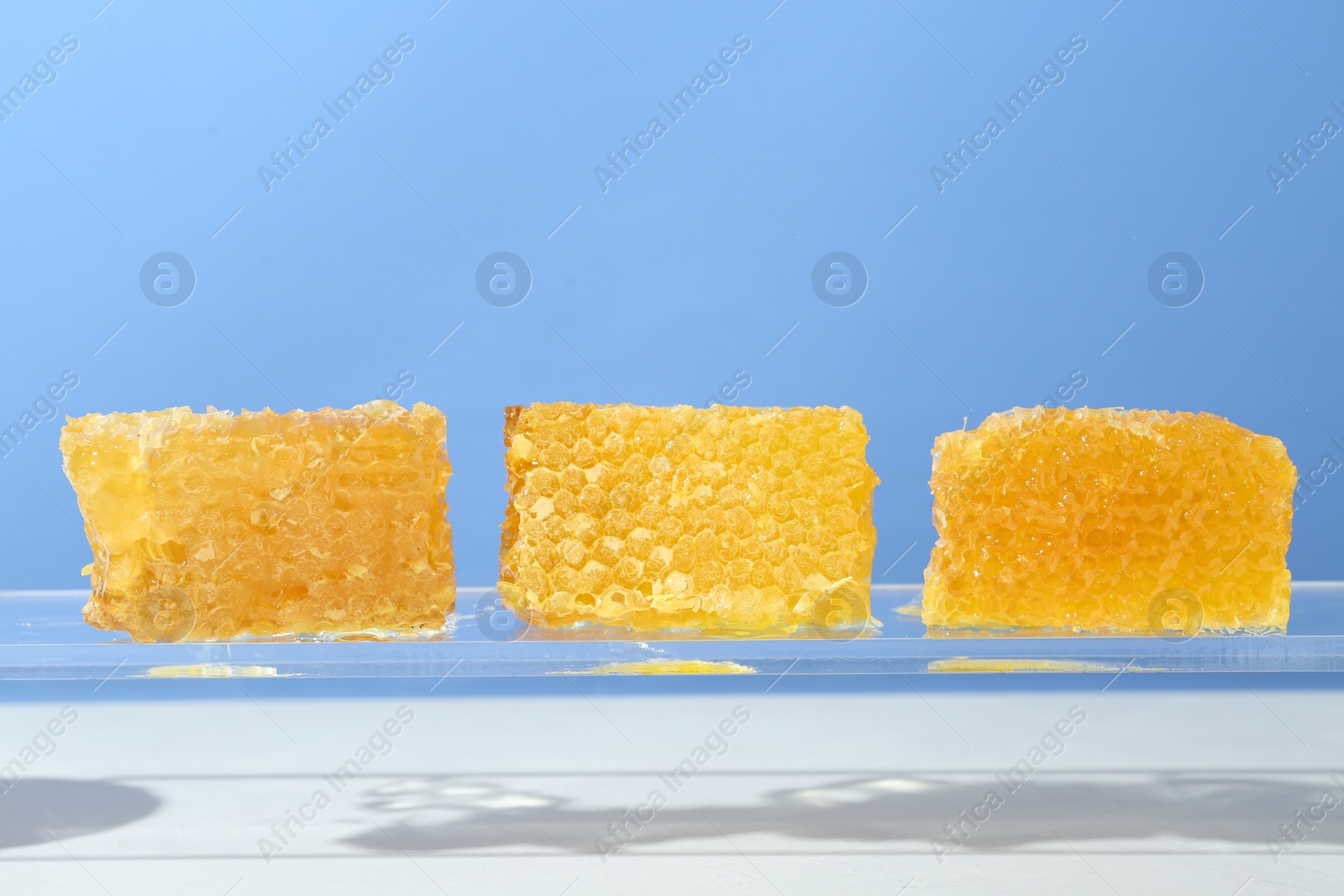 Photo of Natural honeycombs with tasty honey against light blue background