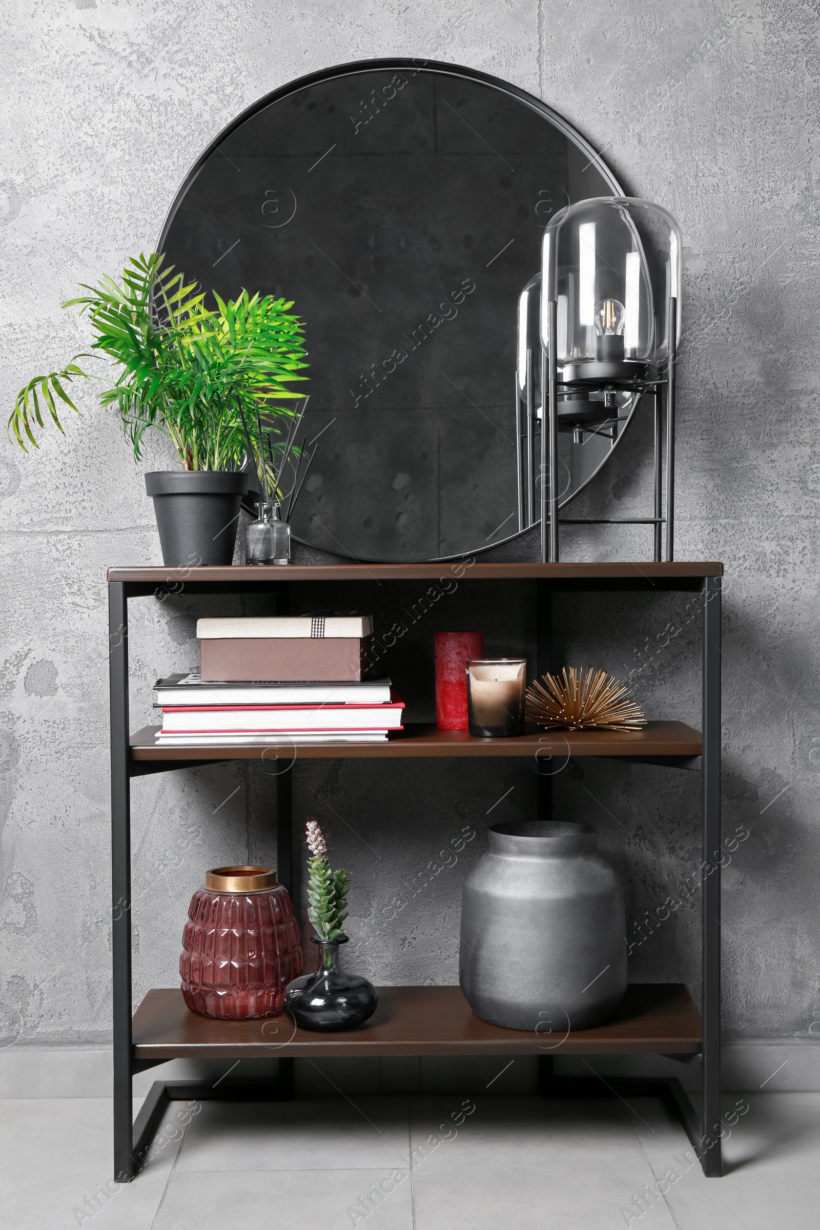 Photo of Stylish round mirror, lamp and houseplant on stand indoors. Interior design