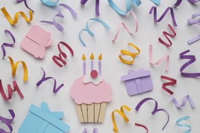 Birthday party. Paper cupcake, gift boxes and confetti on white background, flat lay