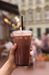 Photo of Woman holding takeaway plastic cup with cold coffee drink outdoors, closeup