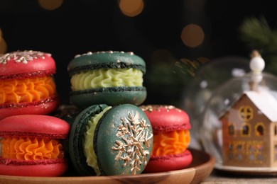 Photo of Beautifully decorated Christmas macarons on wooden table against blurred lights, closeup