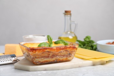 Tasty cooked lasagna in baking dish on light table