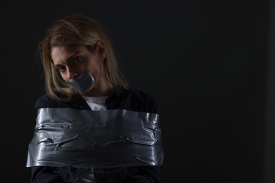 Photo of Woman taped up and taken hostage on dark background. Space for text