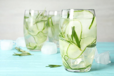 Photo of Glasses of refreshing cucumber lemonade on light blue table, space for text. Summer drink