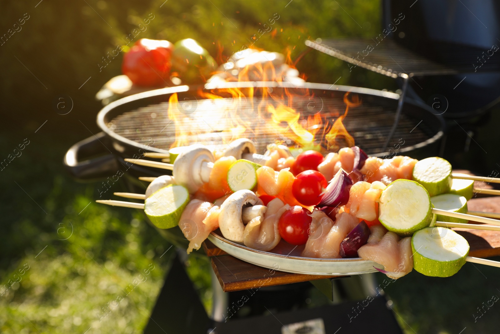 Photo of Skewers with meat and vegetables near barbecue grill outdoors, closeup
