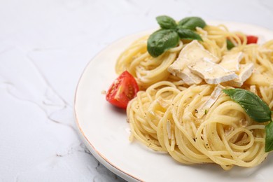Photo of Delicious pasta with brie cheese, tomatoes and basil leaves on white textured table, closeup. Space for text