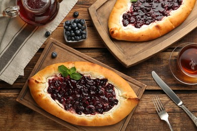 Photo of Delicious sweet cottage cheese pastry with cherry jam served on wooden table, flat lay