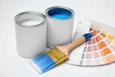Photo of Cans of paint, brush and palette on white background