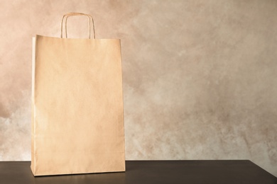 Mockup of paper shopping bag on table against color background