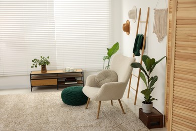 Photo of Comfortable armchair, table and houseplants in stylish room. Interior design