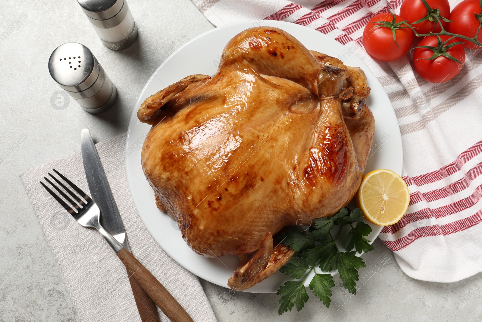 Photo of Tasty roasted chicken with parsley and lemon served on light grey table, flat lay